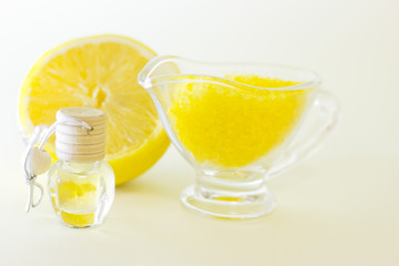 Fruit aromatherapy concept with essential oil in glass bottles, a bowl of bath sea salt and lemon, white background, close up