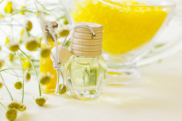 Fruit aromatherapy concept with essential oil in glass bottles, a bowl of bath sea salt, flowers and lemon, white background, close up