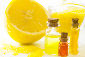 Fruit aromatherapy concept with essential oil in glass bottles, a bowl of bath sea salt, lemon, white background, close up