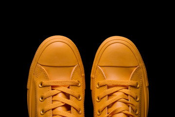 Yellow sneakers on a black background. Fashionable sneakers of yellow color against a dark background.