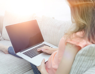 Fototapeta premium young woman working with laptop sitting on sofa