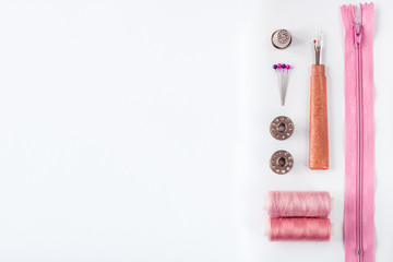 Sewing supplies and accessories for needlework. Spools of thread and other equipment pink colour that uses a tailor to sew clothes on white background.