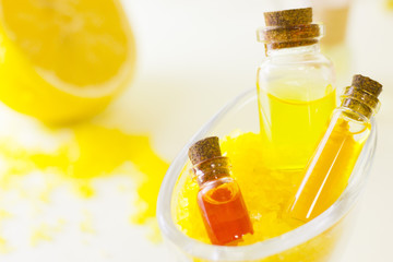 Fruit aromatherapy concept with essential oil in glass bottles, a bowl of bath sea salt, lemon, white background, close up