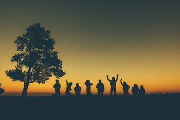 Group friend jumping on mountain silhouettes of sunsets background.