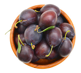 prune plums in wooden bowl on white