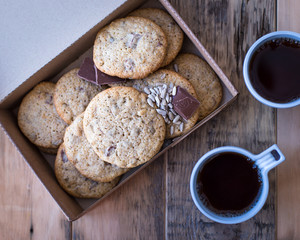 Homemade cookies from whole wheat flour with chocolate and seeds, on a wooden table in a cardboard box