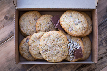Homemade cookies from whole wheat flour with chocolate and seeds, on a wooden table in a cardboard box