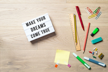 Make your dreams come true written on lightbox in office as flatlay