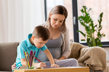 pregnant mother and son with workbook at home