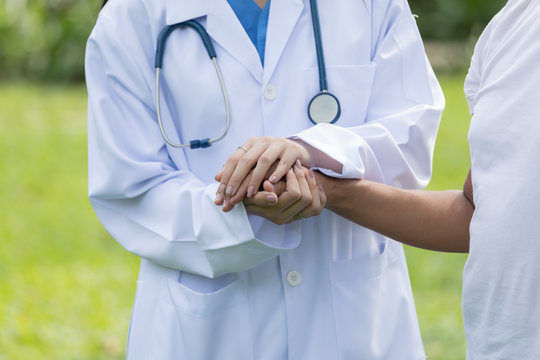 Woman doctor hold hands elder patient 's hand in  park of hospital