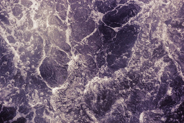 The surface of the sea with waves, foam and bubbles, purple abstract background