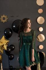 Beautiful girl in a dress with balloons. A party. A green dress. Curly long hair.