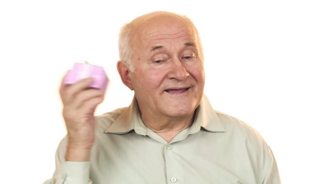 Happy grandpa smiling listening to a gift box guessing what is inside