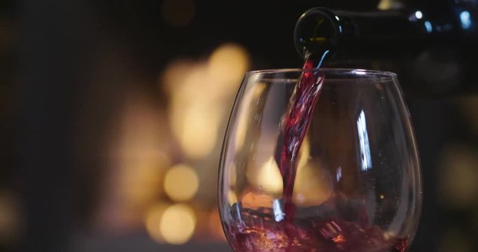 In winter, before the fireplace, is poured, tasted red wine in a glass. Concept of: relax, restaurant, wine, somelier.