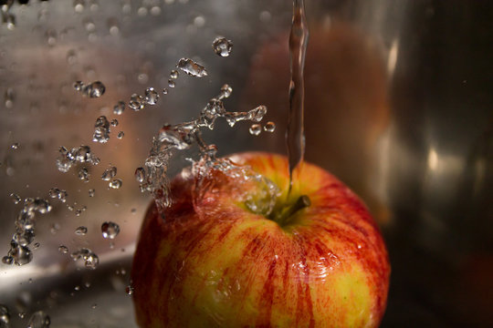 washing apples with splashes of water and lots of waterdrops on a steel background