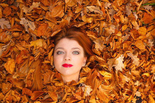 Young woman covered by leaves.