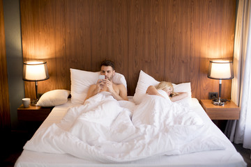 Fototapeta na wymiar Young man looking at phone while woman sleeping