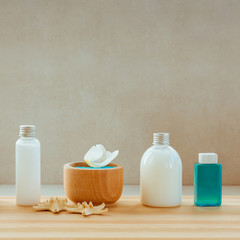 Bottles of oil, body lotion and bowl with spa salt in bowl on wooden shelf.