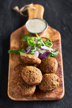 fresh fried vegan falafel with dipping suace on wooden bread board