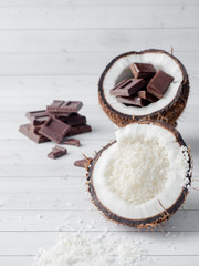 Fresh organic coconut broken into two parts with chocolate on a rustic wooden background