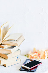 a stack of old books, phone, and e-book, concept of the development of technology, gadgets and love to read on a white background