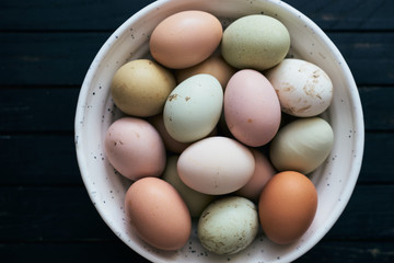 Raw colorful organic chicken eggs in a bowl top view