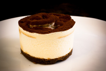 MOUSSE TIRAMISU SERVED ON A WHITE PLATE. DARK BACKGROUND
