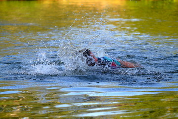 Swimmer floating in river in water splashes