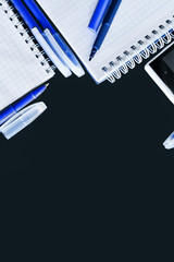 Office background stationery: notepads and spring, pen, marker on black background (for chalk), top view, copyspace under your text