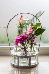 Bouquet of flowers in glass bottles and metal basket. Windowsill.
