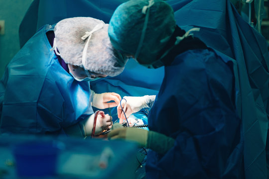 surgeons in hospital operating room with surgery instruments ready for cardiovascular surgery interventions with electrocautery in surgeon hand and all technology equipment for open heart microsurgery