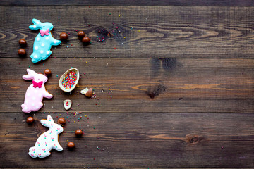 Easter composition. Easter sweet gift. Chocolate eggs near cookies in shape of Easter bunny on dark wooden background top view space for text