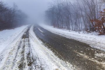 Obraz na płótnie Canvas Snowy road in a misty forest