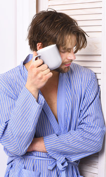 Man with beard in blue dressing gown on white background.