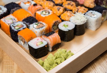 Big sushi and roll set with wasabi on wooden tray