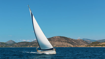Naklejka na ściany i meble Yacht boat with white sails in the Sea near the coasts of the Islands.