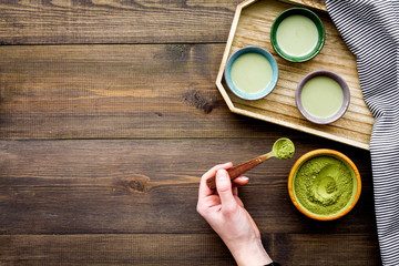 Japanise tea ceremony with matcha tea. Bowl with powder and cups with beverage on tablecloth on dark wooden background top view copy space