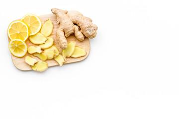 Fresh ginger root and lemon slices pattern on cutting board on white background top view copy space