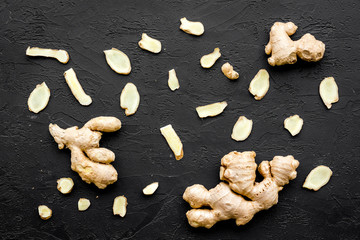 Whole and sliced ginger roots on black background top view