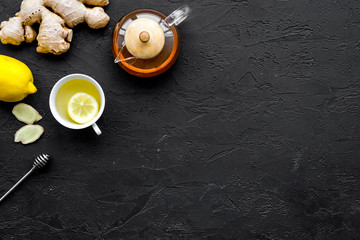 Tea for cure colds. Cup, teapot, ginger root and lemon on black background top view copy space