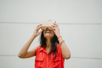 A young Indian Asian woman tries VR (Virtual Reality) goggles for the first time and is surprised and delighted. She is smiling and laughing whilst looking up.