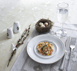 on the table napkin with a plate vegetable stew green onion glass fork knife and willow branches salt pepper sauce 