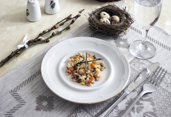 on the table napkin with a plate vegetable stew green onion glass fork knife and willow branches salt pepper sauce