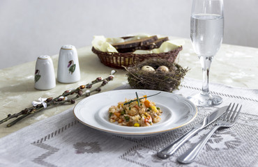 on the table napkin with a plate vegetable stew green onion glass fork knife and willow branches salt pepper sauce