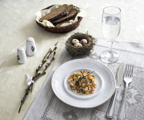 on the table napkin with a plate vegetable stew green onion glass fork knife and willow branches salt pepper sauce