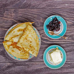 Freshly prepared pancakes for breakfast near jam, a glass of milk and butter, top view, horizontal.
