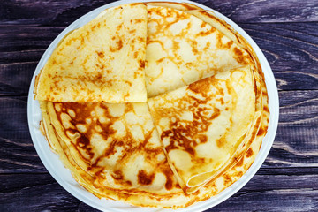Pancakes on a white plate with honey and a cup of milk. Tasty breakfast.