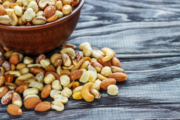 Mix nuts in earthenware on a wooden background.