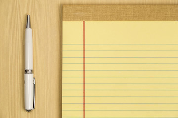 White pen adjecent to a yellow notepad