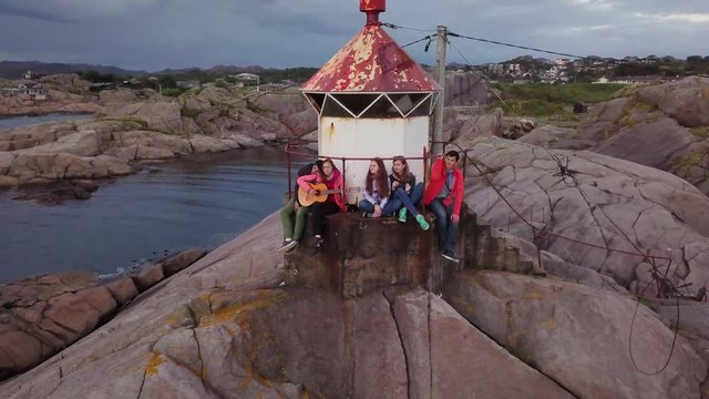 Aerial view from drone on beautiful lighthouse during sunset. Group of people enjoying evening on the rocks. 4k footage. Norway.